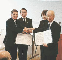 協定書を取り交わす佐藤市長（左）と小川理事長（右）